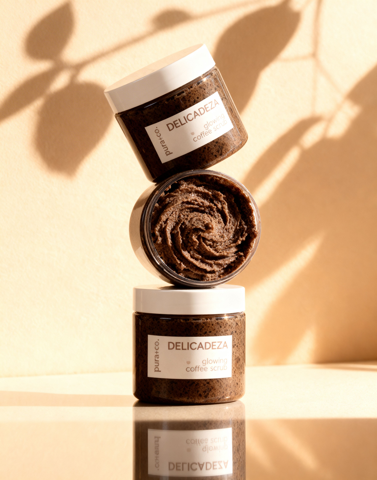 Pura+Co | A column of three Delicadeza Coffee Scrubs sits on top of each other on a reflective surface | Exfoliante Natural |  Oatmeal honey Scent | Handmade Skin Care | Puerto Rico