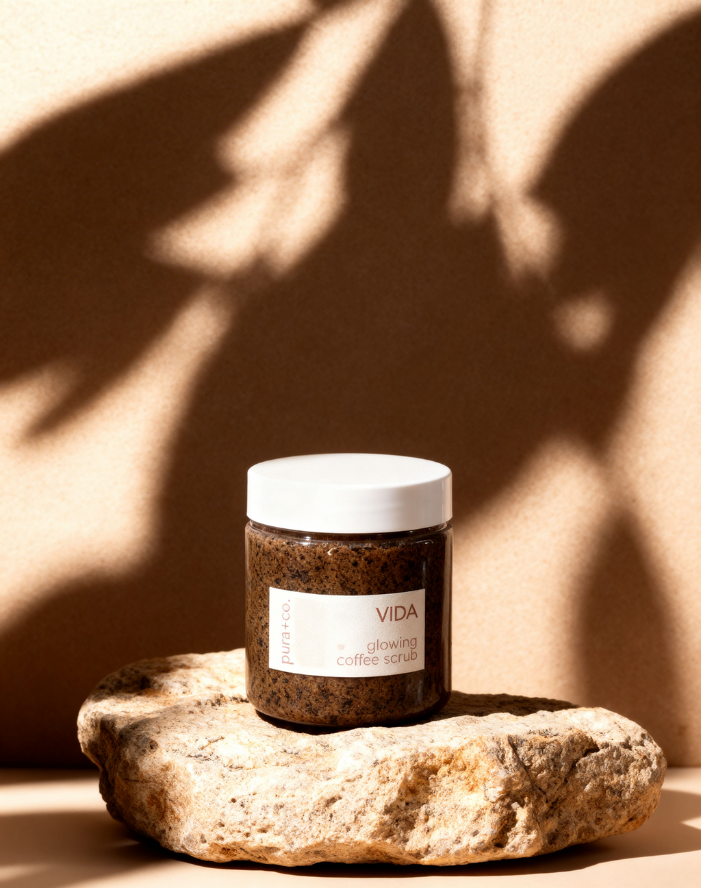 Pura+Co | The Vida Coffee Scrub jar sits on a stone surface | Exfoliante Natural |  Amber Mandarin Scent | Handmade Skin Care | Puerto Rico