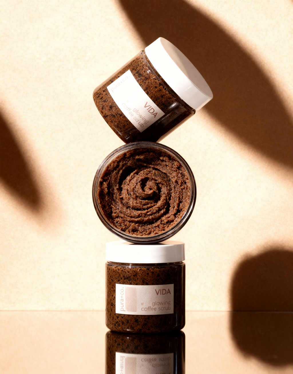 Pura+Co | A column of three Vida Coffee Scrubs sits on top of each other on a reflective surface | Exfoliante Natural |  Amber Mandarin Scent | Handmade Skin Care | Puerto Rico